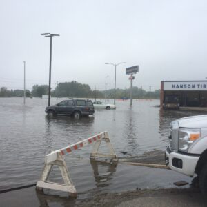 Flooding showing cars and a tire shop inundated with water